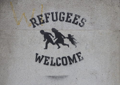 A « Refugees Welcome » sign spray painted on the eastern side of the Malet Street Gardens, Bloomsbury, London Borough of Camden (Wikimedia Commons)
